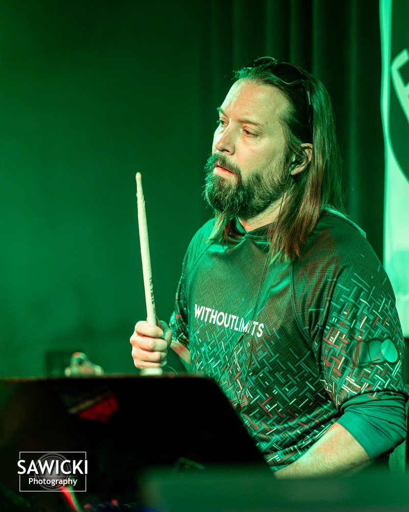 Chris Ellison live, drums, stick raised